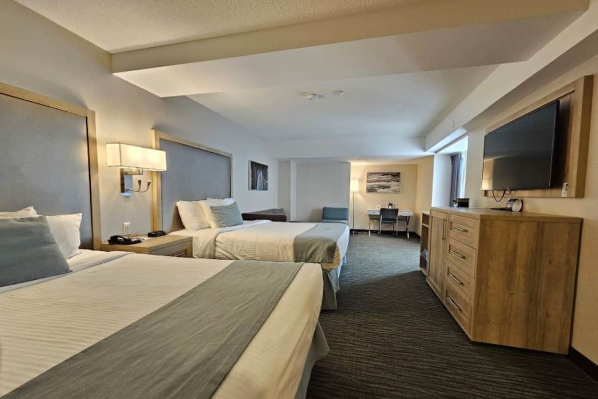 Ein Hotelzimmer mit zwei Betten, einem Schreibtisch, einem Fernseher und einer Minibar.