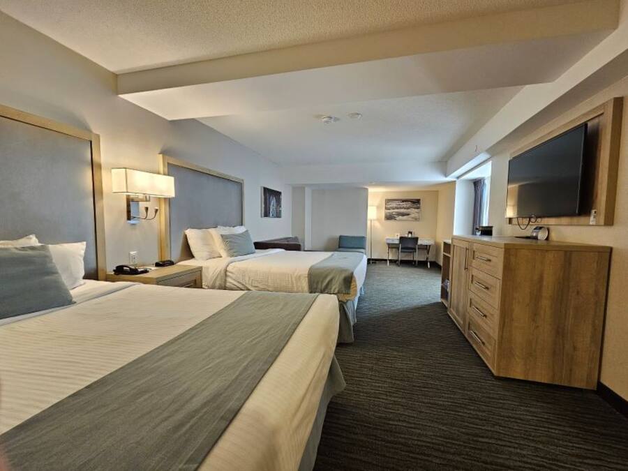 Une chambre d’hôtel avec deux lits, un bureau, une télévision et un minibar.