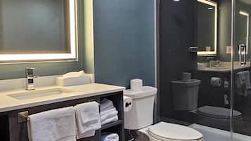 A modern bathroom with a vanity, toilet, and glass-enclosed shower.