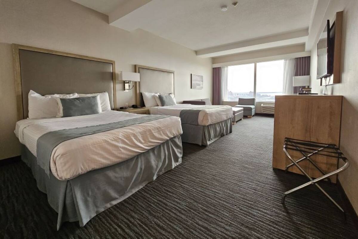 Ein Hotelzimmer mit zwei Betten, einem Schreibtisch und Blick auf die Stadt.
