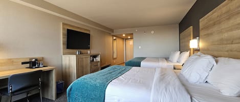 Habitación de hotel con dos camas, un escritorio, una cafetera, un televisor y un espejo.