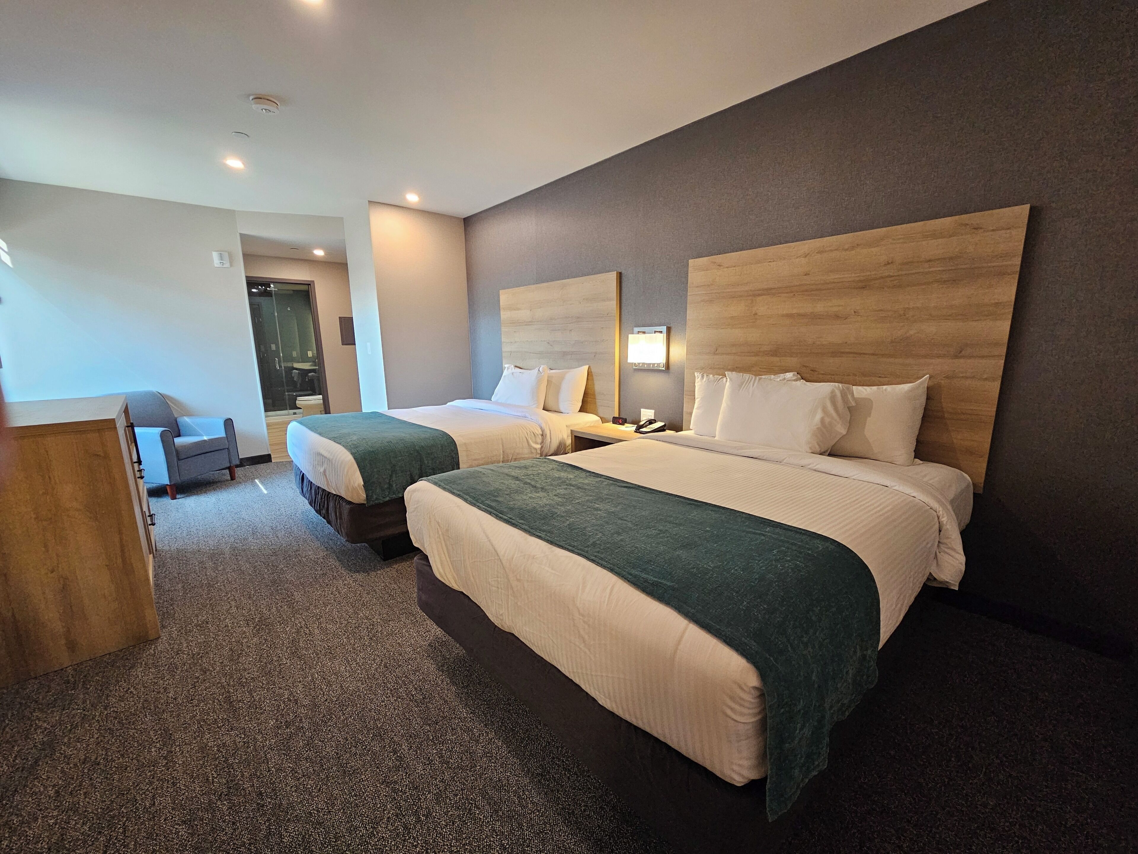 A hotel room with two beds, a desk, and a chair.