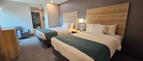 A hotel room with two beds, a desk, and a chair.