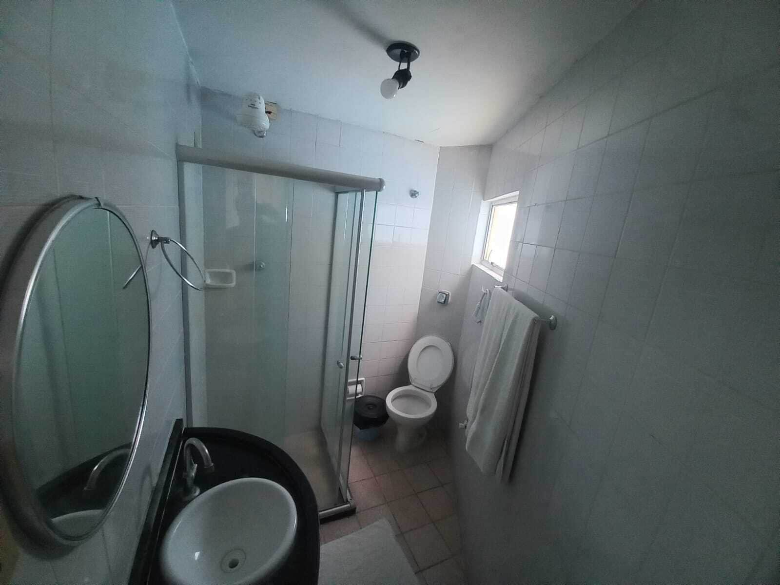 Un bany petit amb un envà de dutxa de vidre, un rentapeus i un vàter.