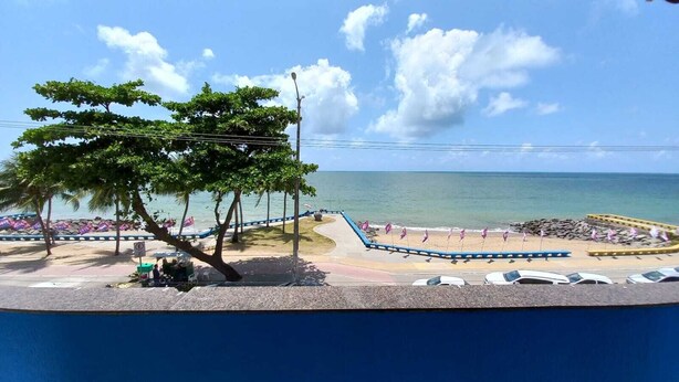 A beach with a curved walkway, palm trees, and a view of the ocean. - Hotel Samburá (Olinda)