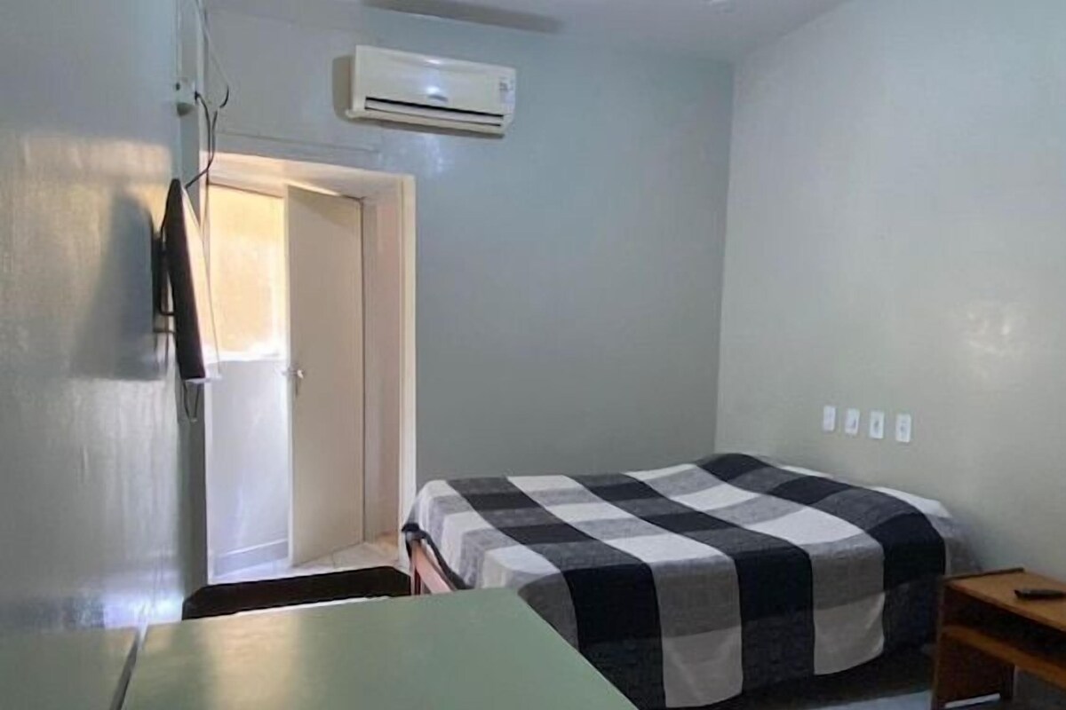 Una habitación pequeña y poco amoblada con una cama, una mesa y una silla.