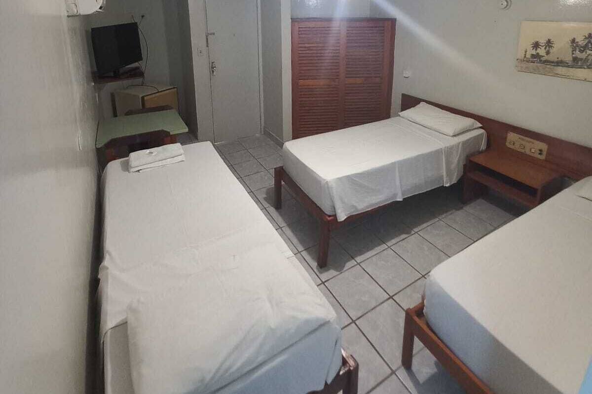 A small, clean room with two single beds, a desk with a chair, a television, and a wardrobe.