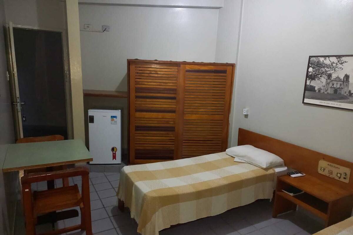 A small, tidy room with a bed, a desk, a chair, and a wardrobe.