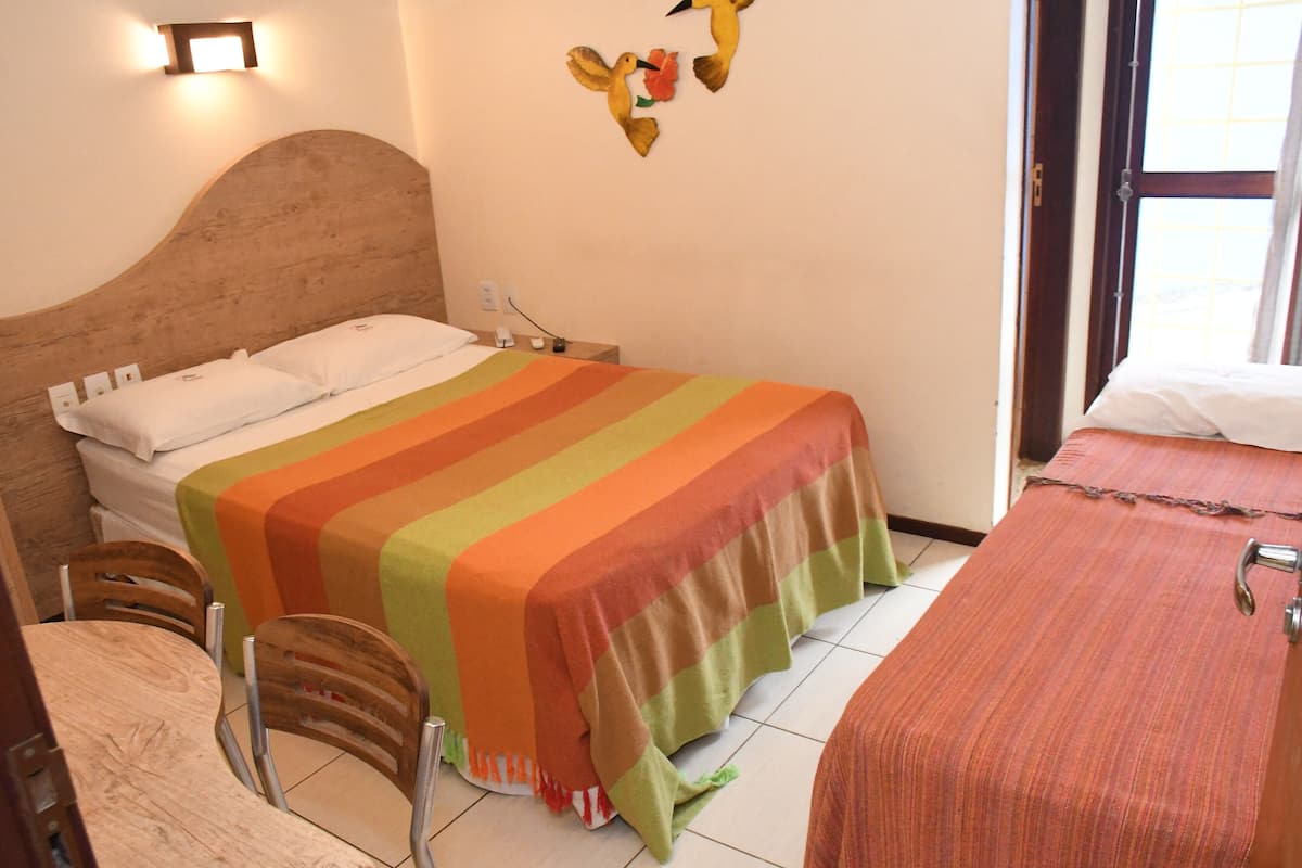 A hotel room with a bed, a small table with chairs, and a window.