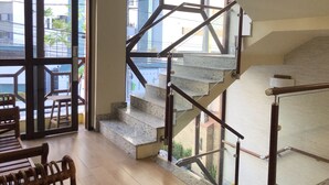 A spacious room with a large window, a staircase with a metal railing, and a wooden bench. - Vitória Praia Hotel (Recife)