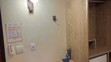 Una pequeña kitchenette con un refrigerador, un gabinete de madera, una silla y un escritorio con una lámpara.