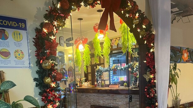 A hotel entrance with a glass door, decorated with a festive wreath and garlands. - Vitória Praia Hotel (Recife)