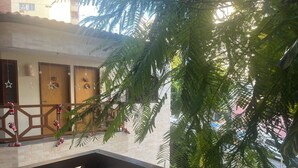 A balcony with a wooden railing, a brick wall, and a view of a parked car and buildings in the background. - Vitória Praia Hotel (Recife)