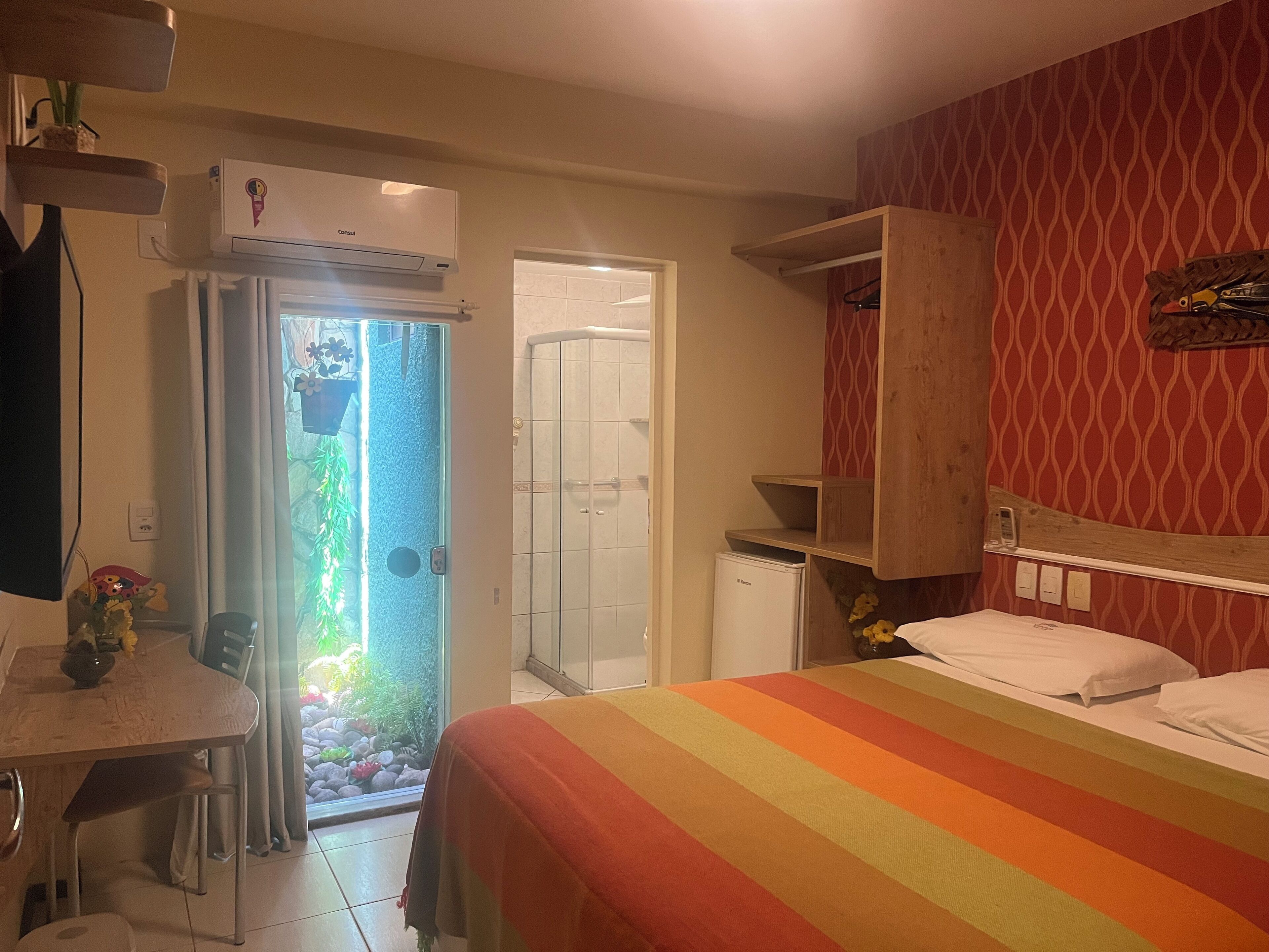 A hotel room with a bed, a desk, a chair, a wardrobe, and a bathroom.