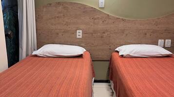 Una habitación con dos camas, cabecero de madera, luz empotrada en la pared y equipo de aire acondicionado.