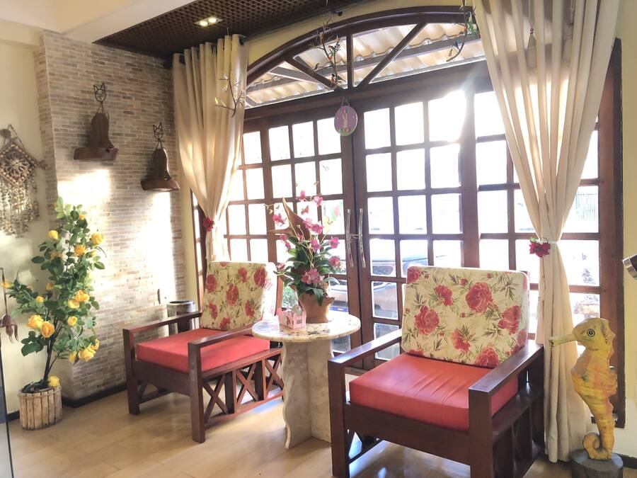 Una habitación acogedora con dos sillas de madera con cojines rojos, una mesita redonda y una planta en maceta.