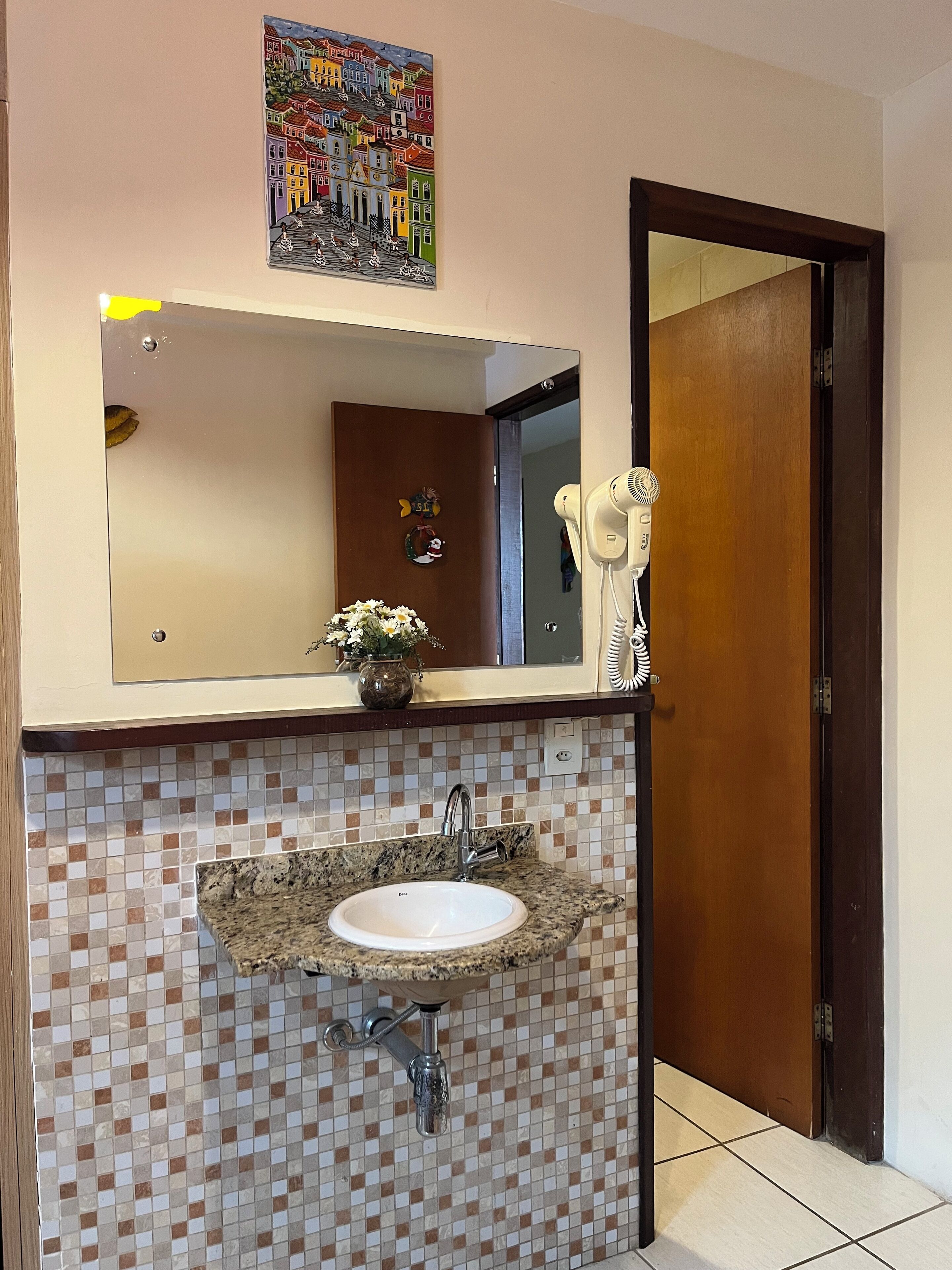Casa de banho com lavatório, espelho e porta.