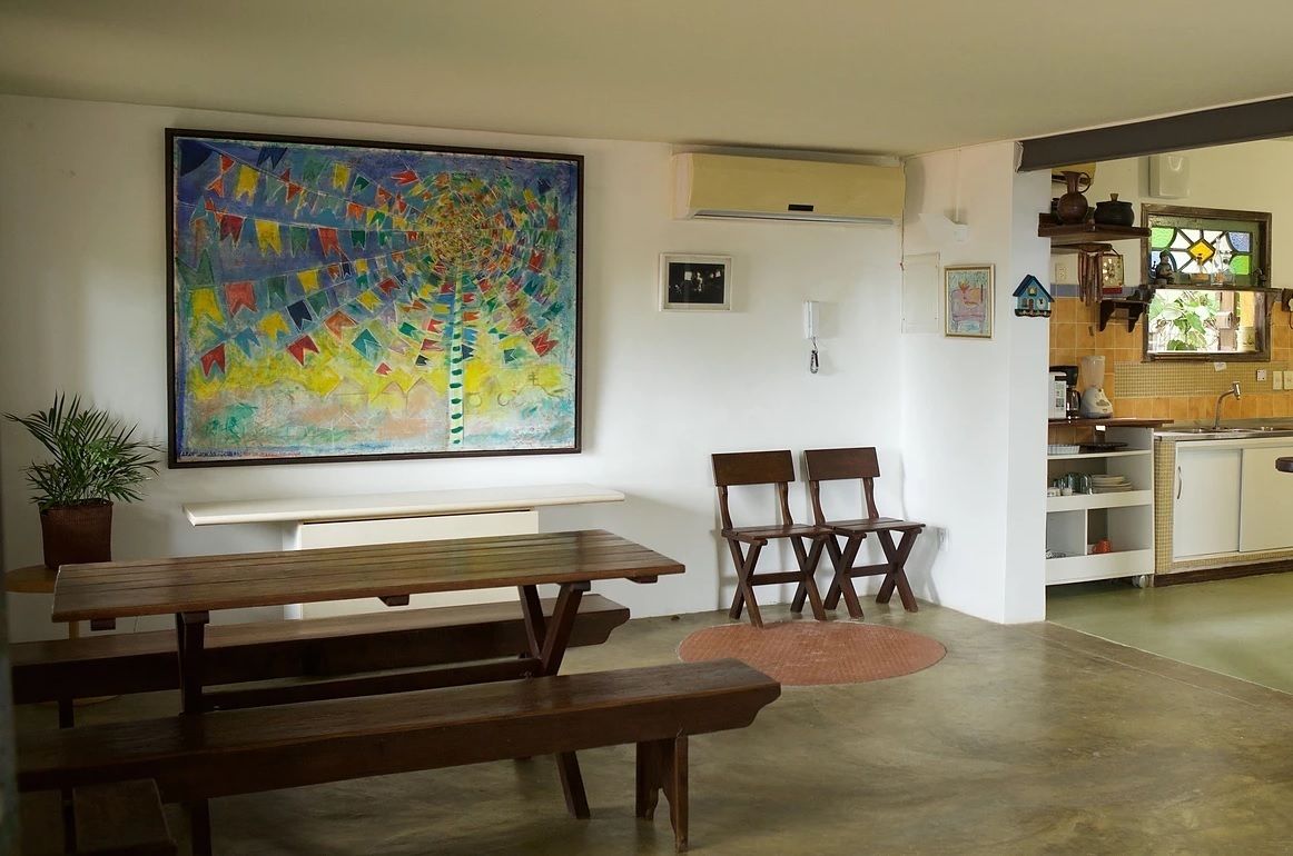 A dining area with a wooden bench, a table, and a colorful abstract painting on the wall.