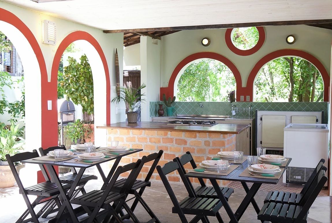 An outdoor patio with tables and chairs, a brick counter with a sink, and a grill area.
