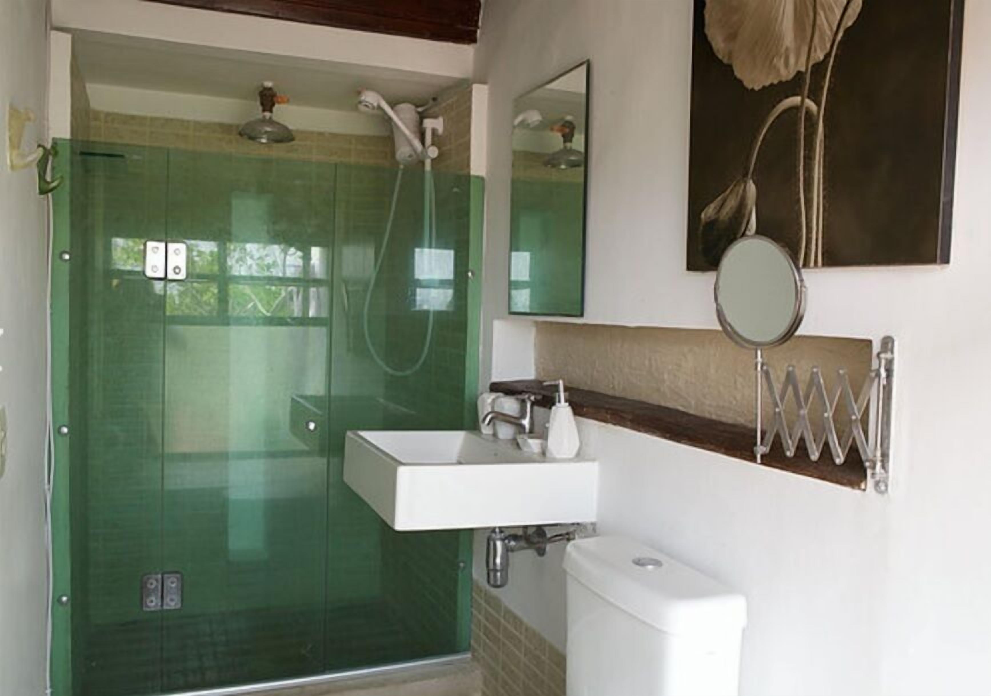 A bathroom with a glass-enclosed shower, a white sink, and a toilet.