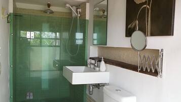 A bathroom with a glass-enclosed shower, a white sink, and a toilet.