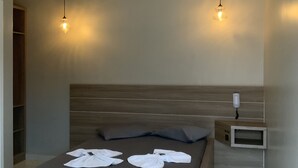 Un dormitorio moderno con una cama de madera, dos lámparas colgantes, una mesita de noche con un teléfono y una televisión integrada.
