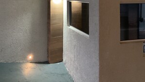 Rincón de una habitación con pared texturizada, panel de madera y una ventana pequeña.