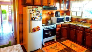 Una cocina con gabinetes de madera, un refrigerador, una estufa y dos microondas.