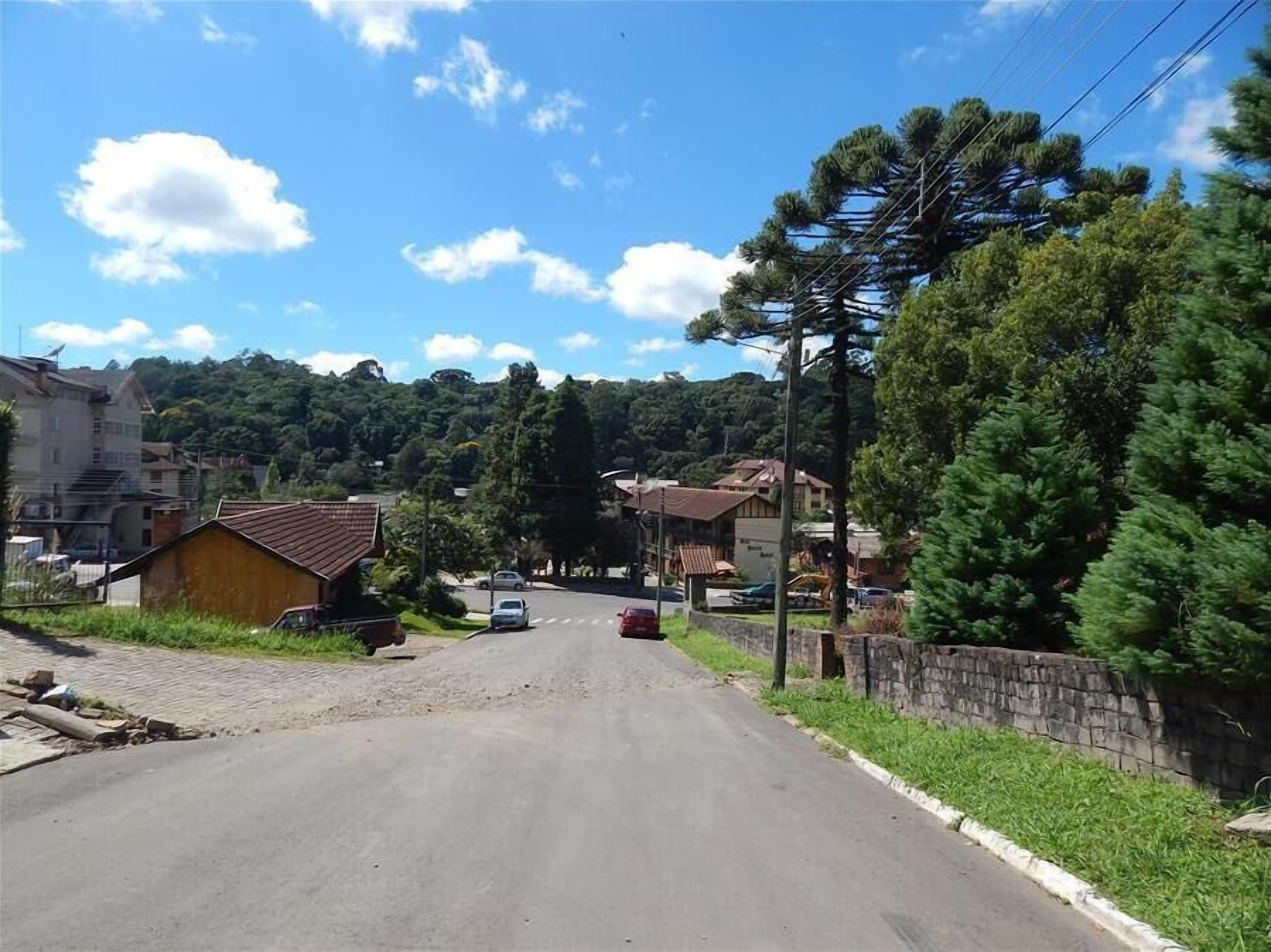 A quiet street with houses, a stone wall, and a clear blue sky.