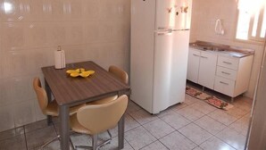 A compact kitchen with a refrigerator, a dining table with chairs, and a small sink. - Apartamento dos Altos Centro de Gramado (Gramado)