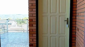 Eine weiße Tür mit einem Schild darüber, eine Fußmatte mit Schriftzug und eine Blumenkomposition auf der Veranda.
