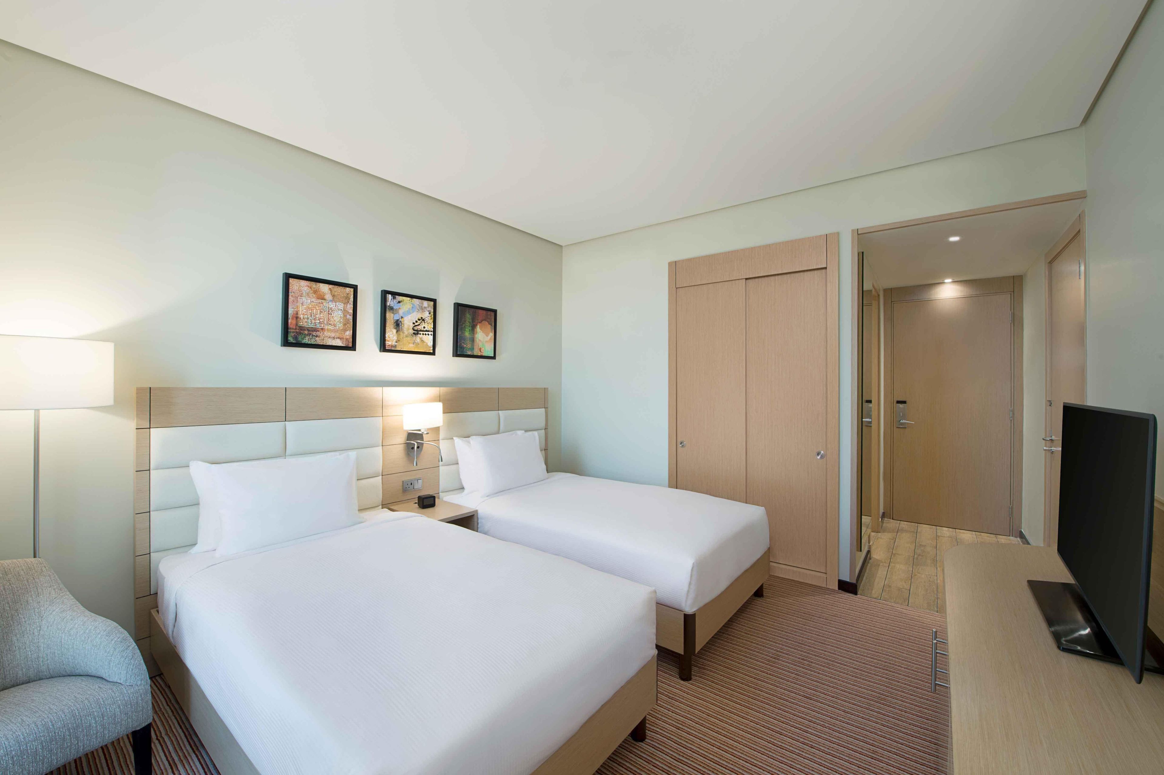 A hotel room with two beds, a TV, and a door leading to a bathroom.
