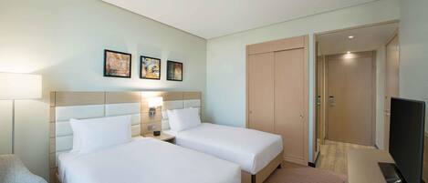 A hotel room with two beds, a TV, and a door leading to a bathroom.