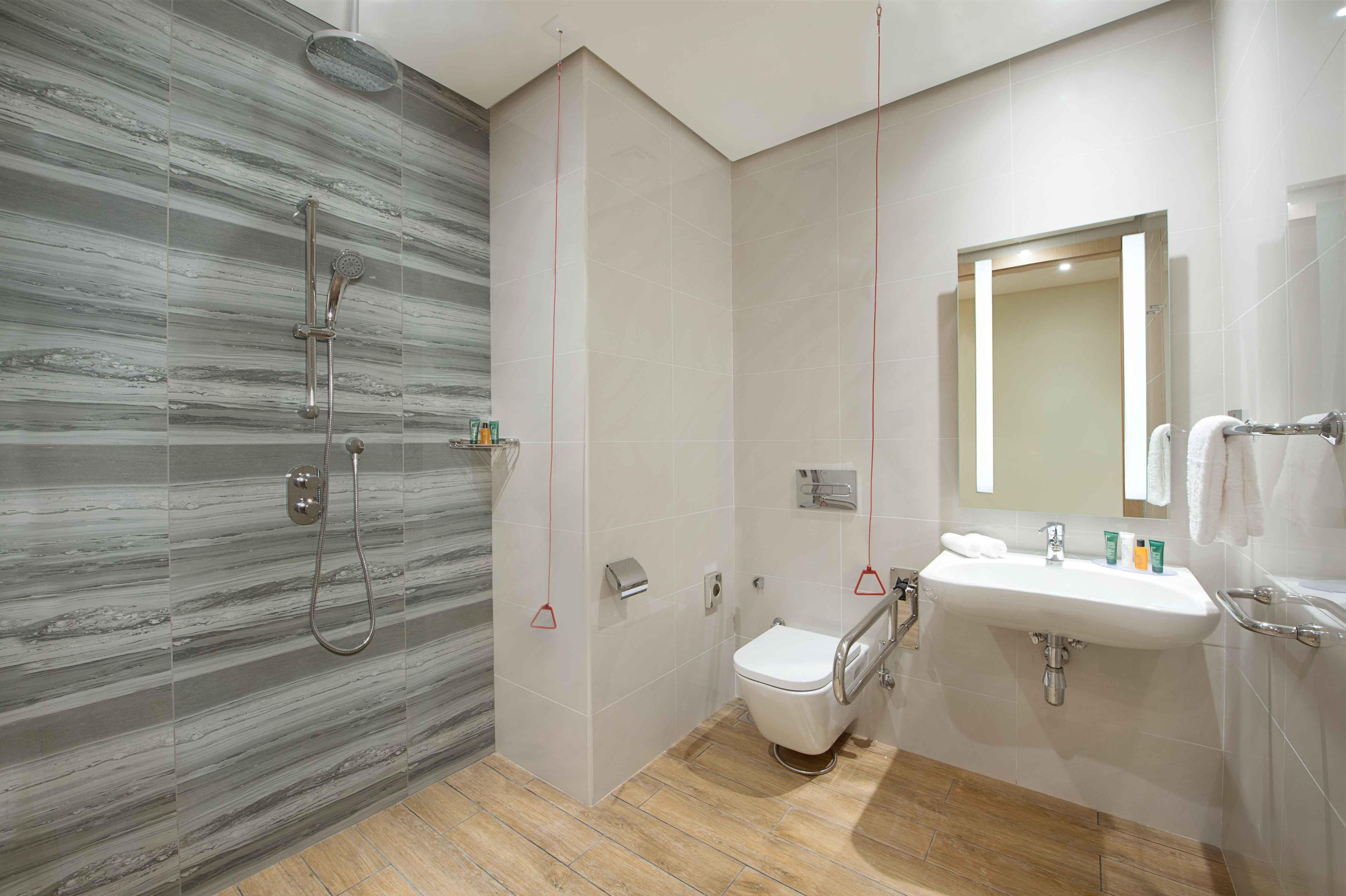 A modern bathroom with a shower, toilet, sink, and a mirror.