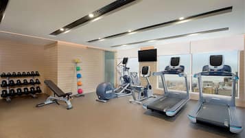 A gym with treadmills, a bench, dumbbells, and a rowing machine.