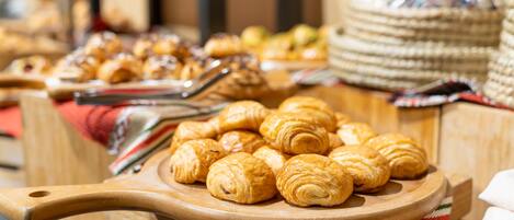 Una tabla de madera con croissants y una bandeja de pan.