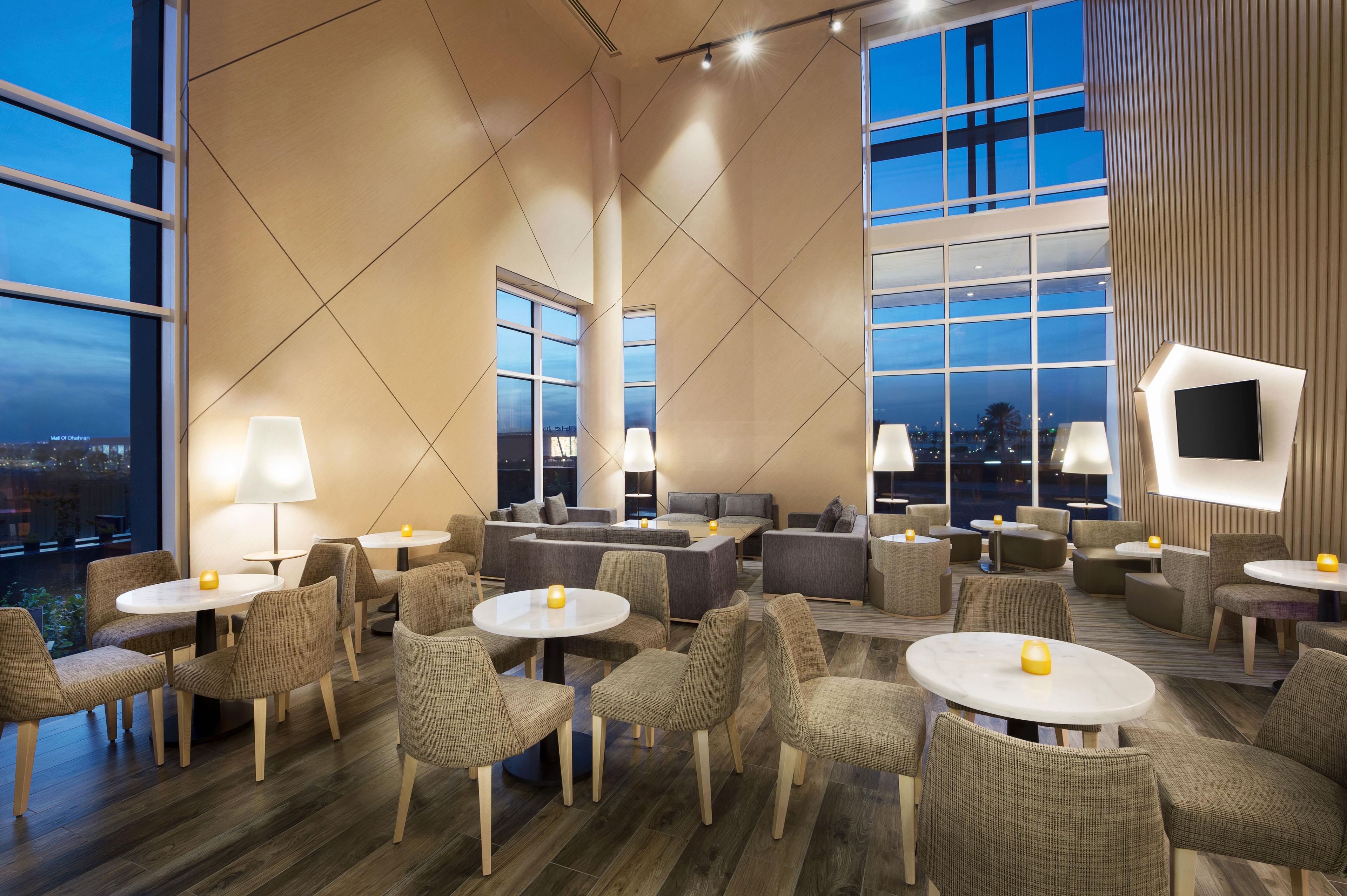 A modern lounge area with multiple seating options, including sofas and chairs, arranged around tables.
