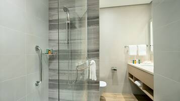 A modern bathroom with a glass-enclosed shower, a toilet, and a vanity with a mirror.