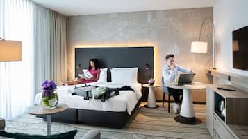 Une chambre d’hôtel moderne avec un grand lit, un bureau, un ordinateur portable et une carte accrochée au mur.