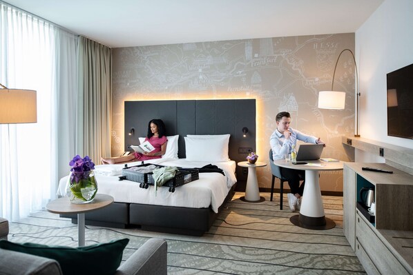 Una habitación de hotel moderna con una cama grande, un escritorio, una computadora portátil y un mapa en la pared.