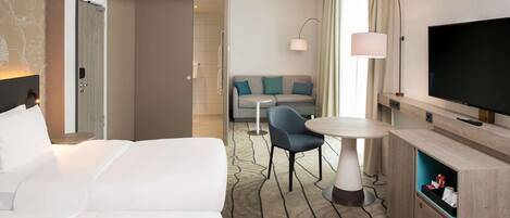 Una habitación de hotel con una cama, un sofá, un televisor, una lámpara y una mesita.