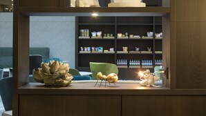 A modern interior with a wooden display shelf, a green chair, and a shelf with various items. - Hyatt Place Frankfurt Airport (Frankfurt)