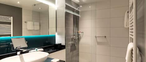Un baño moderno con un lavamanos grande de color blanco, mampara de ducha de cristal y encimera negra.