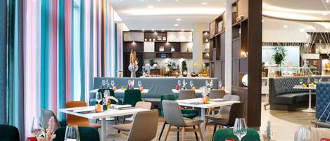 A modern restaurant interior with multiple dining tables, chairs, and a bar area.