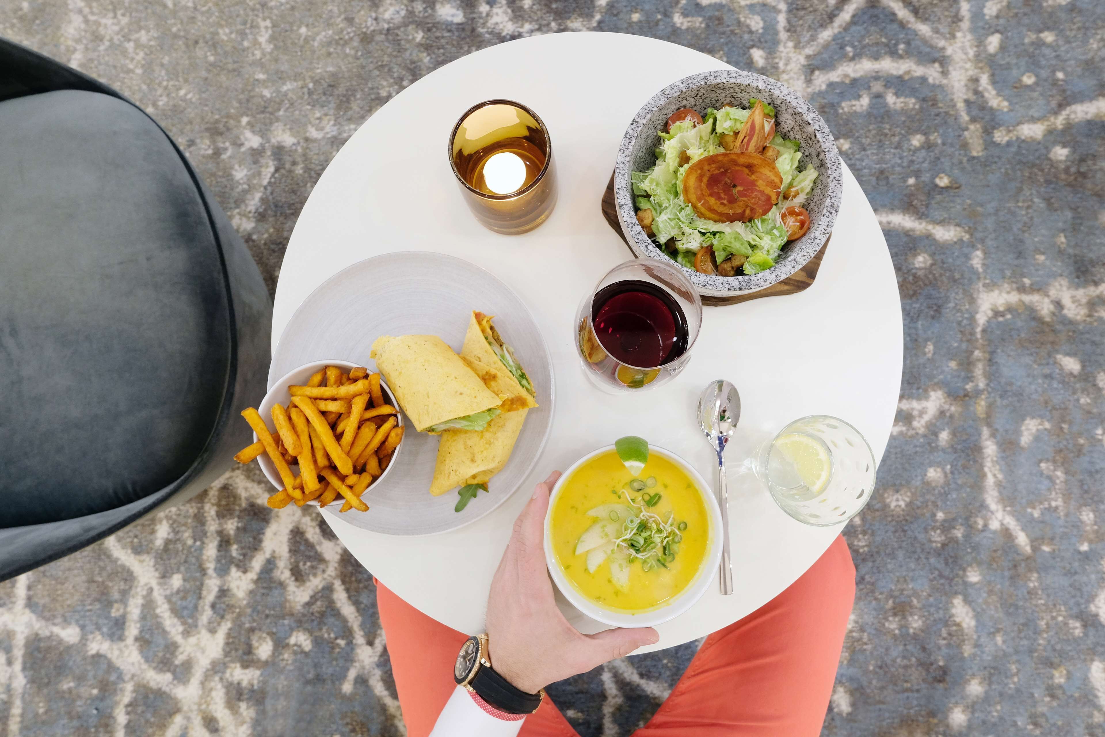 A table with a sandwich, fries, soup, and drinks.