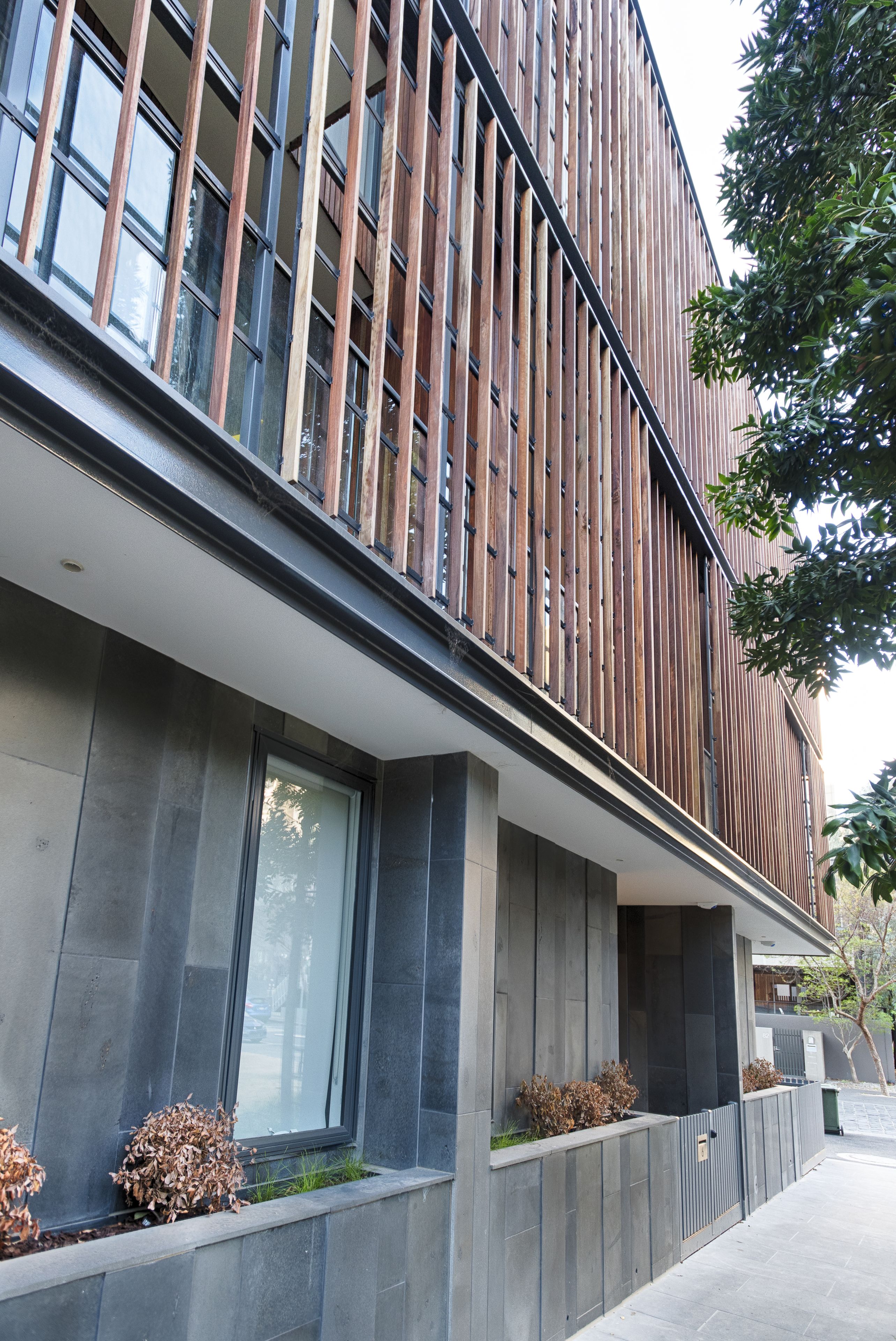 A modern building with vertical wooden slats, large windows, and a flat roof.