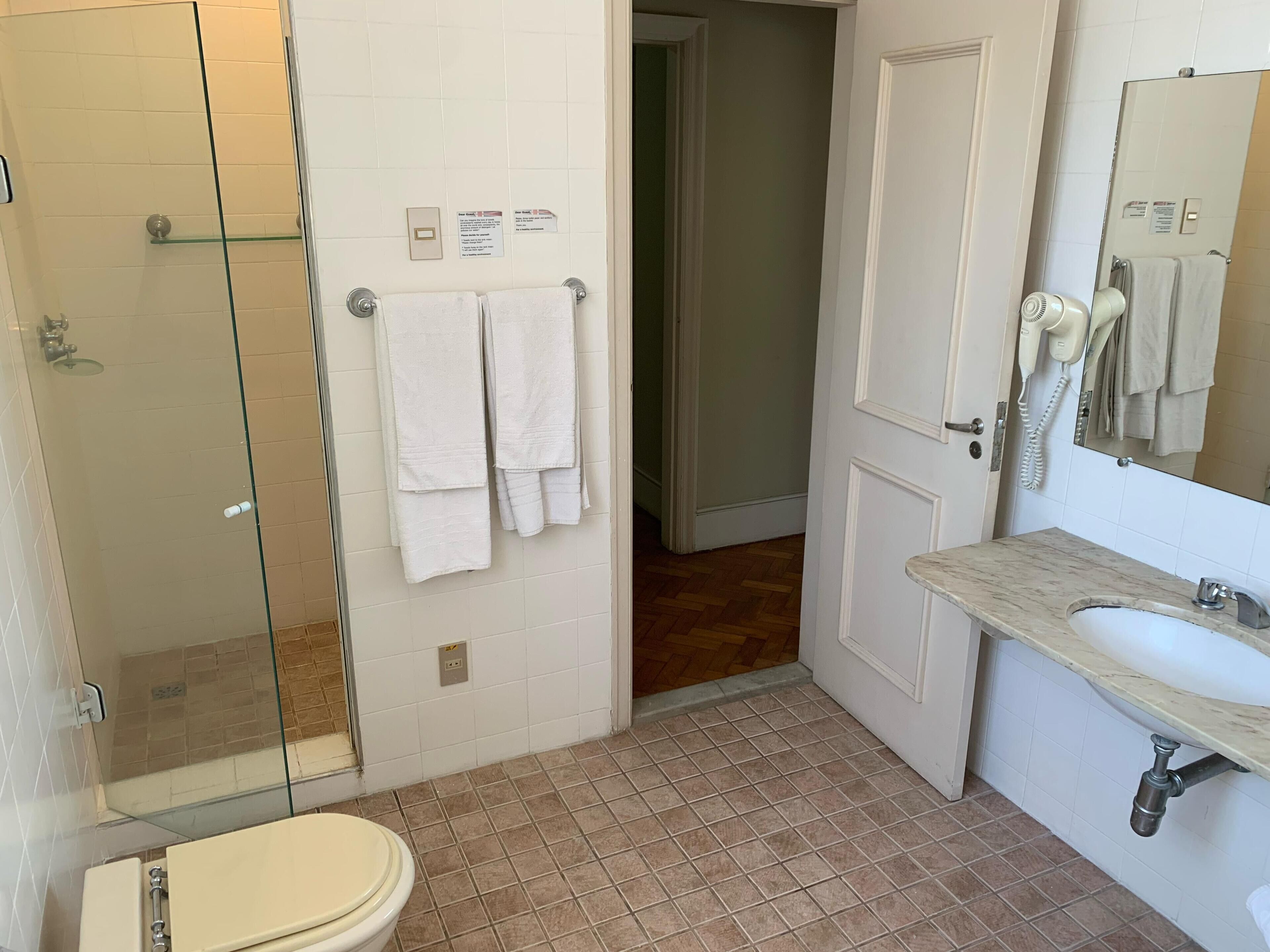 Une salle de bain avec une douche à parois de verre, des toilettes, un lavabo avec un plan de toilette en marbre et un miroir.