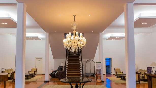 A spacious lobby with a grand chandelier, a central staircase, and seating areas. - Hotel Escola Bela Vista (Volta Redonda)