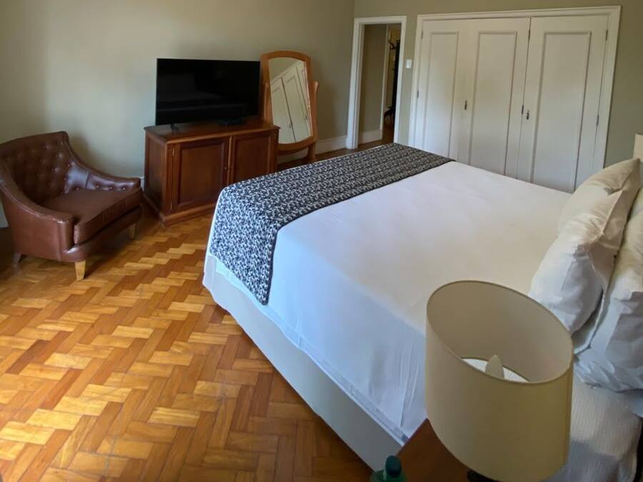 A bedroom with a large bed, a television, a wardrobe, and a chair.