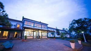 A two-story building with a covered patio area, potted plants, and a bench. - Hotel Escola Bela Vista (Volta Redonda)